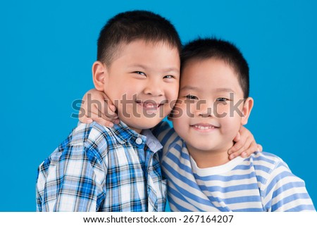 Cheerful Chinese brothers hugging and looking at the camera