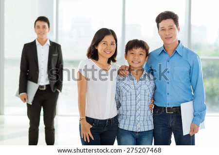 Portrait of happy Vietnamese family and realtor in the background: real estate concept