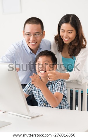 Happy Vietnamese family using computer together at home