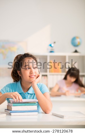 Smiling Vietnamese girl daydreaming in class