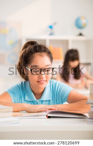 Vietnamese schoolgirl reading book in the class