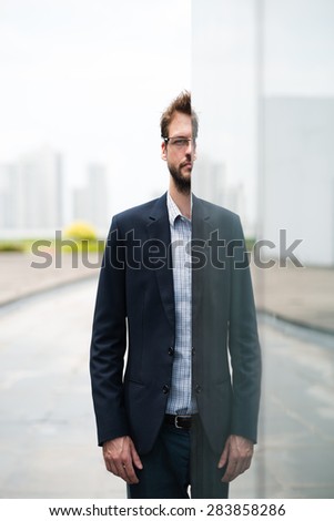 Portrait of businessman emerging from behind a glassy wall