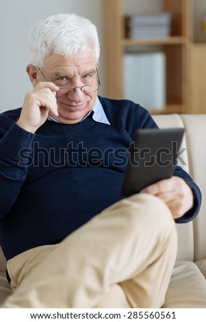 Positive senior man using digital tablet at home