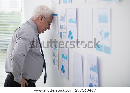 Stressed and tired senior businessman leaning against office wall
