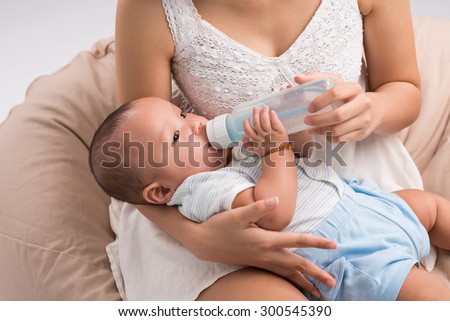 Cropped image of mother feeding one month son from the milk bottle