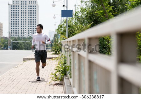 Vietnamese young man jogging outdoors in the morning