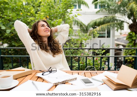 Female writer resting at her workplace with hands behind her head