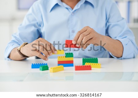 Businessman connecting lego details at his place of work
