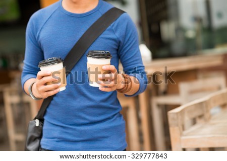 Cropped image of man holding two cups of take-out coffee
