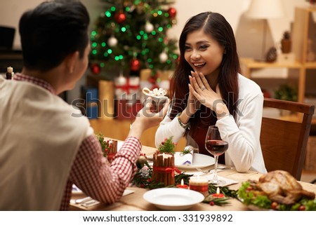 Man giving small present to his girlfriend at the Christmas dinner