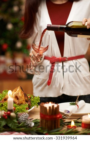 Woman pouring red wine into glass at the Christmas dinner