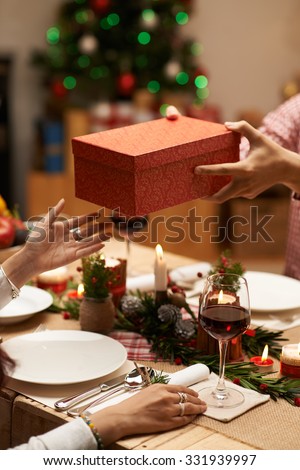 Hands of woman receiving big box from her husband at the Christmas dinner
