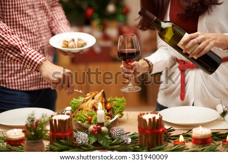 People eating roasted chicken and drinking red wine at Christmas dinner