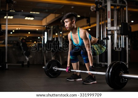 Young woman lifting weights in the gym