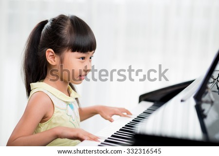 Little Vietnamese girl playing the piano at home