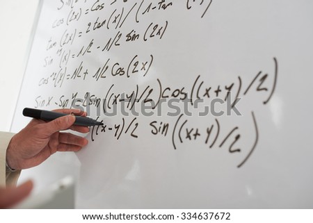 Close-up image of male hand writing math equations on the board