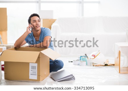 Handsome young man calling on the phone when packing his belongings