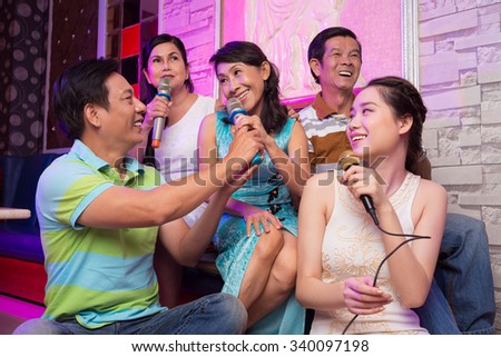Group of cheerful people singing son in karaoke