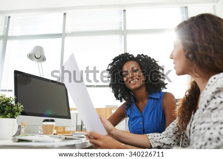 Cheerful African-American female entrepreneur listening to her colleague