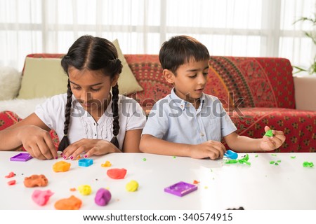 Indian brother and sister playing with playdough at home