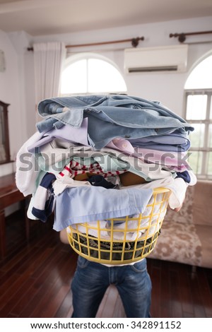 Man holding big basket of dirty clothes: laundry concept
