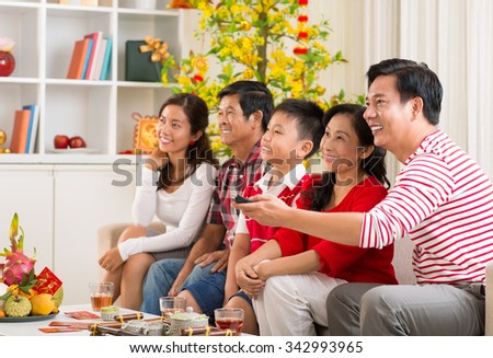 Vietnamese family watching tv at the celebration of Tet