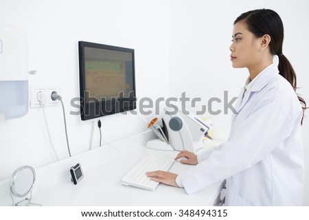 Asian female laboratory assistant checking information on computer