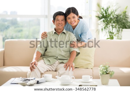Portrait of smiling Vietnamese doctor hugging senior man