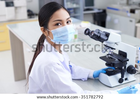 Portrait of pretty laboratory worker in mask looking at camera