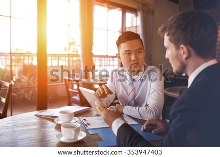 Two businessmen sitting in cafe and discussing business project