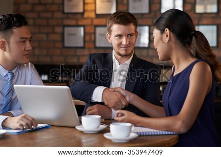Handsome manager greeting woman at business meeting in cafe