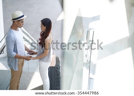 Young couple holding hands and looking at each other at the airport terminal