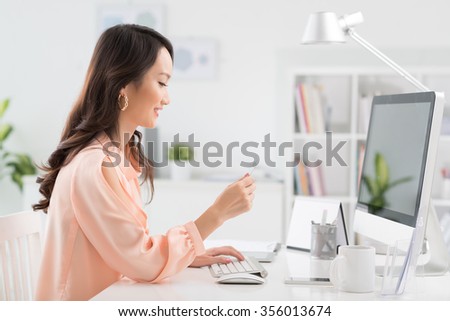 Smiling Chinese woman with credit card shopping online