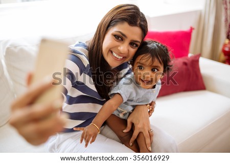 Happy Indian mother taking selfie with little daughter