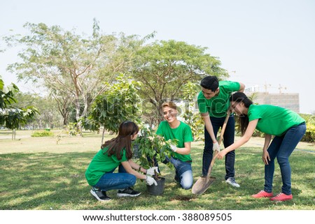 Team of young activists planting tree in the park