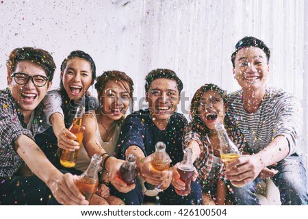 Group of Asian young people clinking bottles of beer with you