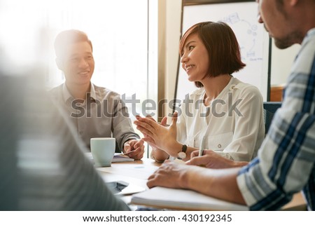Pretty young female entrepreneur talking to her employees at meeting