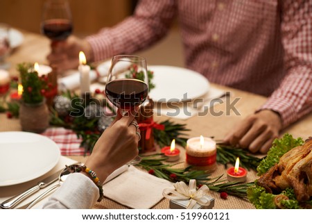 Hands of couple drinking red wine at Christmas table