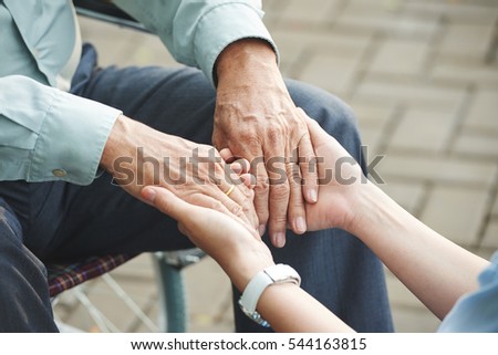 Close-up image of nurse holding hands of mature man