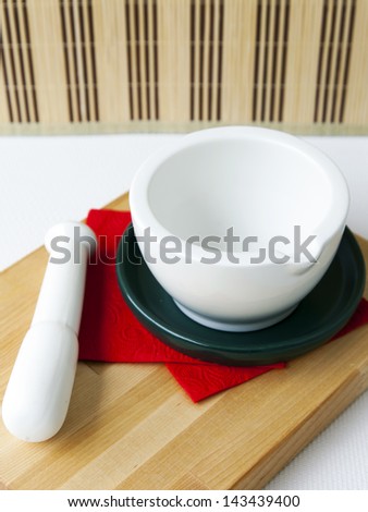 White porcelain mortar with a pestle on a red napkin