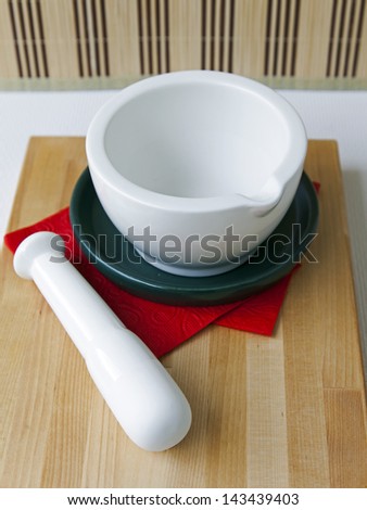 White porcelain mortar with a pestle on a red napkin