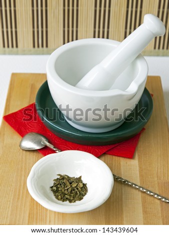 White porcelain mortar with a pestle on a red napkin and spice