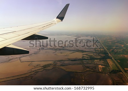 View of the ground and the wing of an airplane window