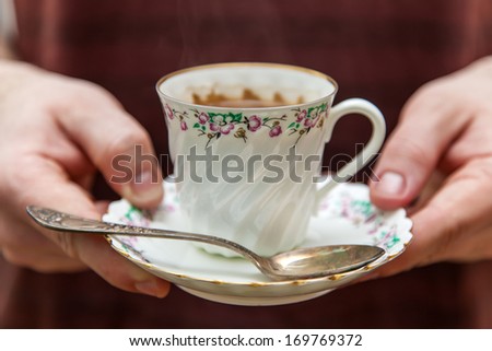 Porcelain cup with coffee in hand of a young man