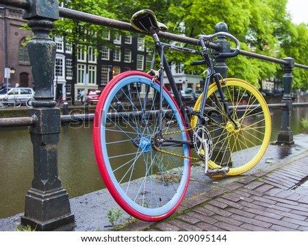 Amsterdam, Netherlands, on July 8, 2014. Bicycles are parked on the city street on the bank of the channel
