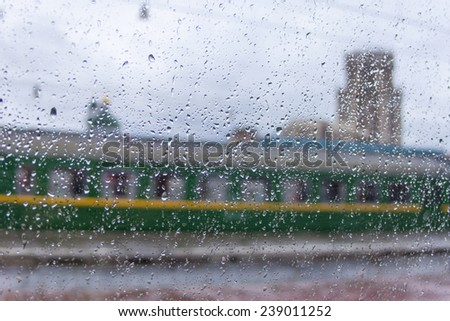 View in rainy weather from a train window on the passing train. Focus on drops on glass