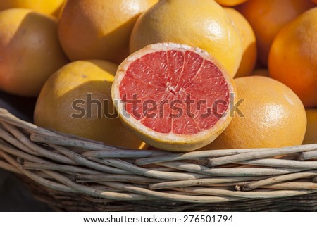 Ripe juicy grapefruits on a show-window of shop of vegetables and fruit and a grapefruit half