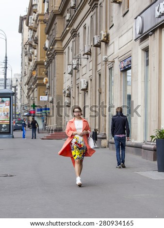 MOSCOW, RUSSIA, on MAY 24, 2015. The woman in a bright raincoat goes down the street Garden and Chernogryazskaya (A garden ring)