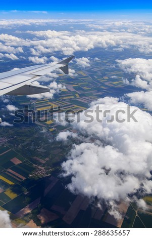 Plane view from the window on picturesque landscape with white clouds