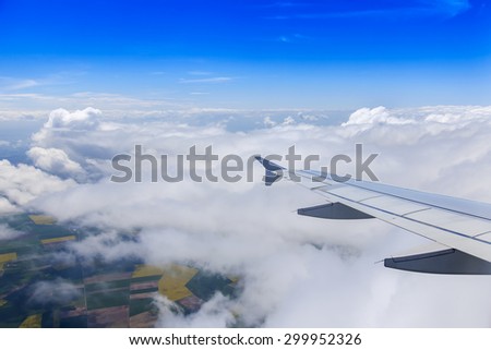 Plane view from the window on picturesque white clouds and wing of the plane